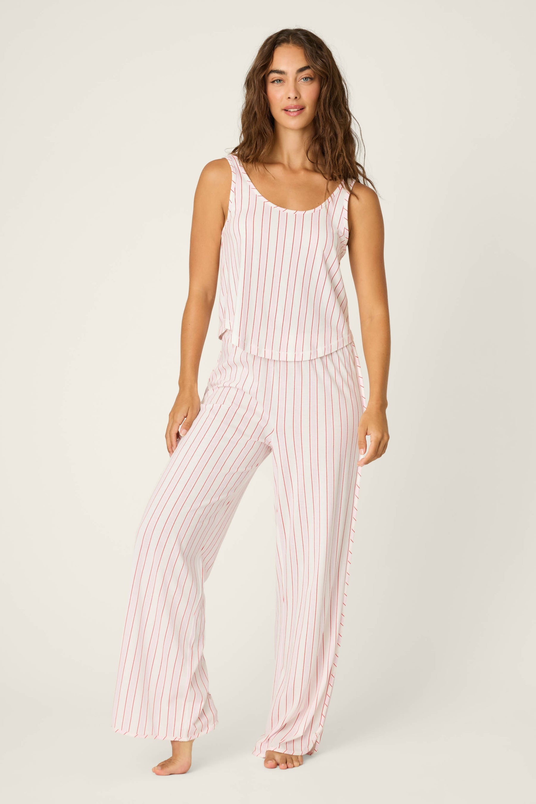 Woman wearing a pink and white striped sleeveless top and pants on a white background