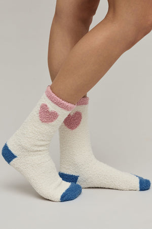 White socks with pink hearts and blue toes worn by a person on a neutral background