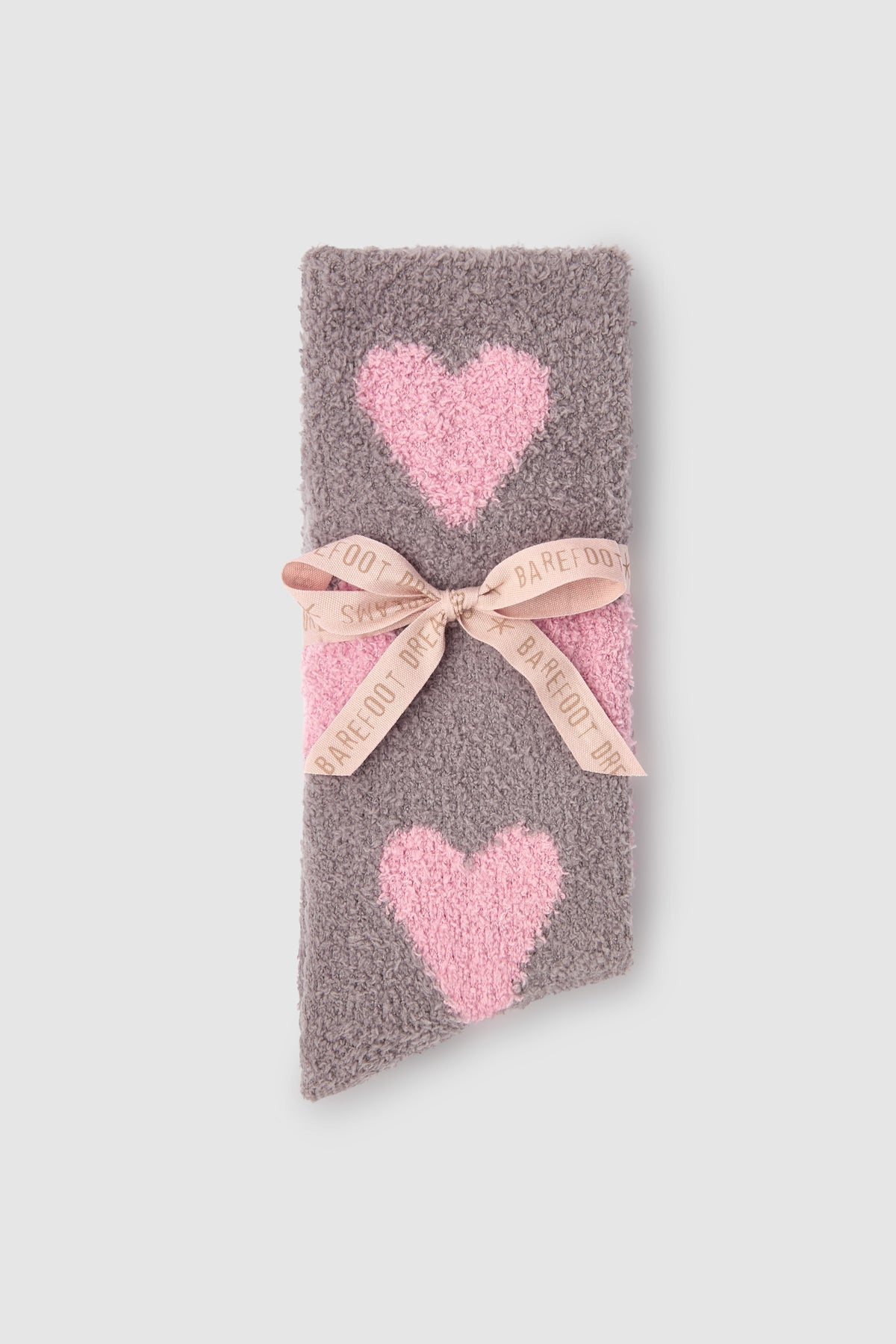 Gray socks with pink heart patterns on a light gray background