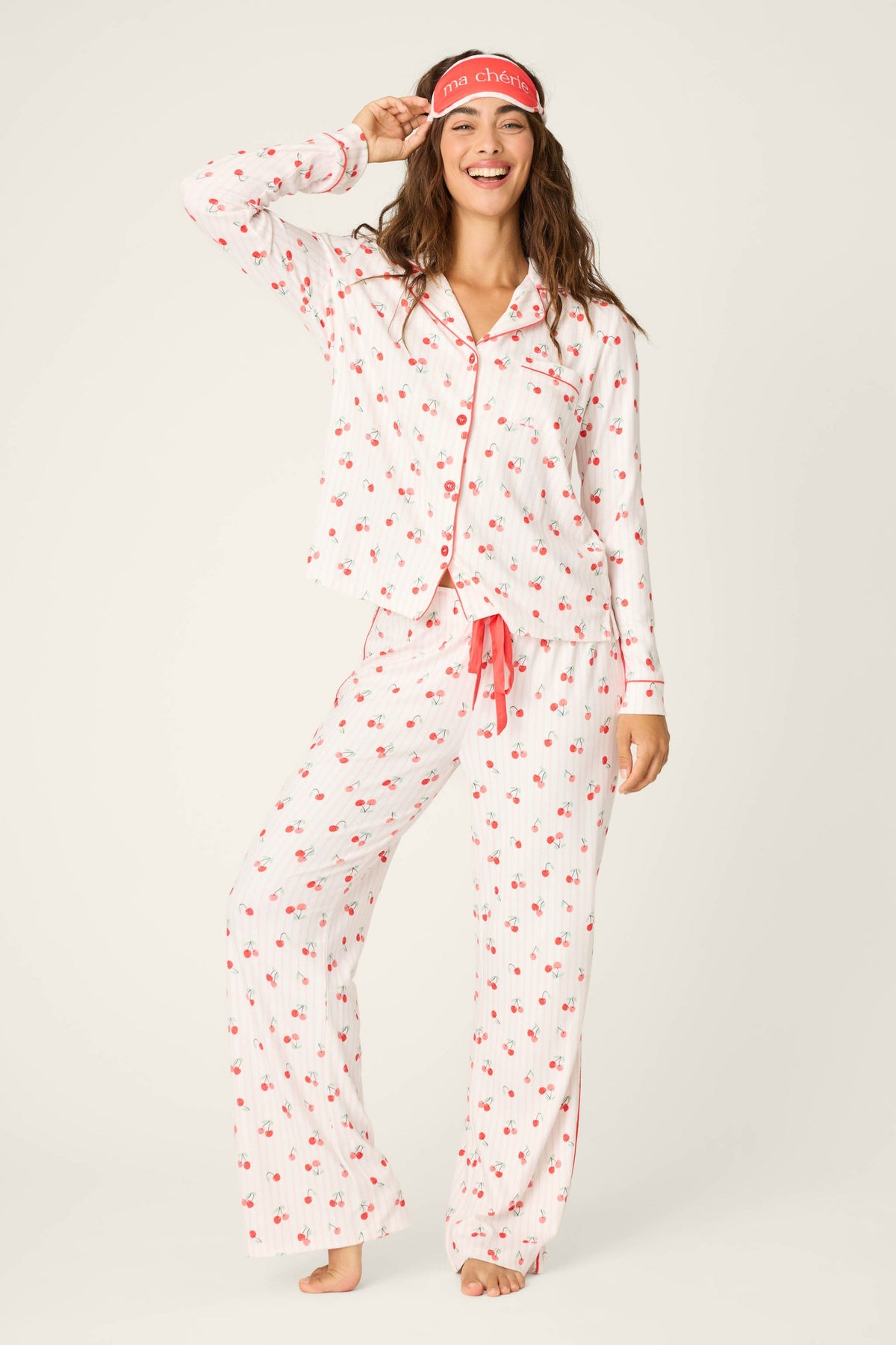 Woman wearing a white pajamas with red floral patterns on a plain background